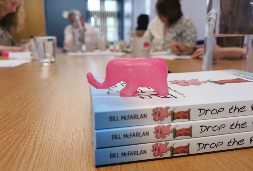 top ten pink elephants, plastic pink elephant on books in training room