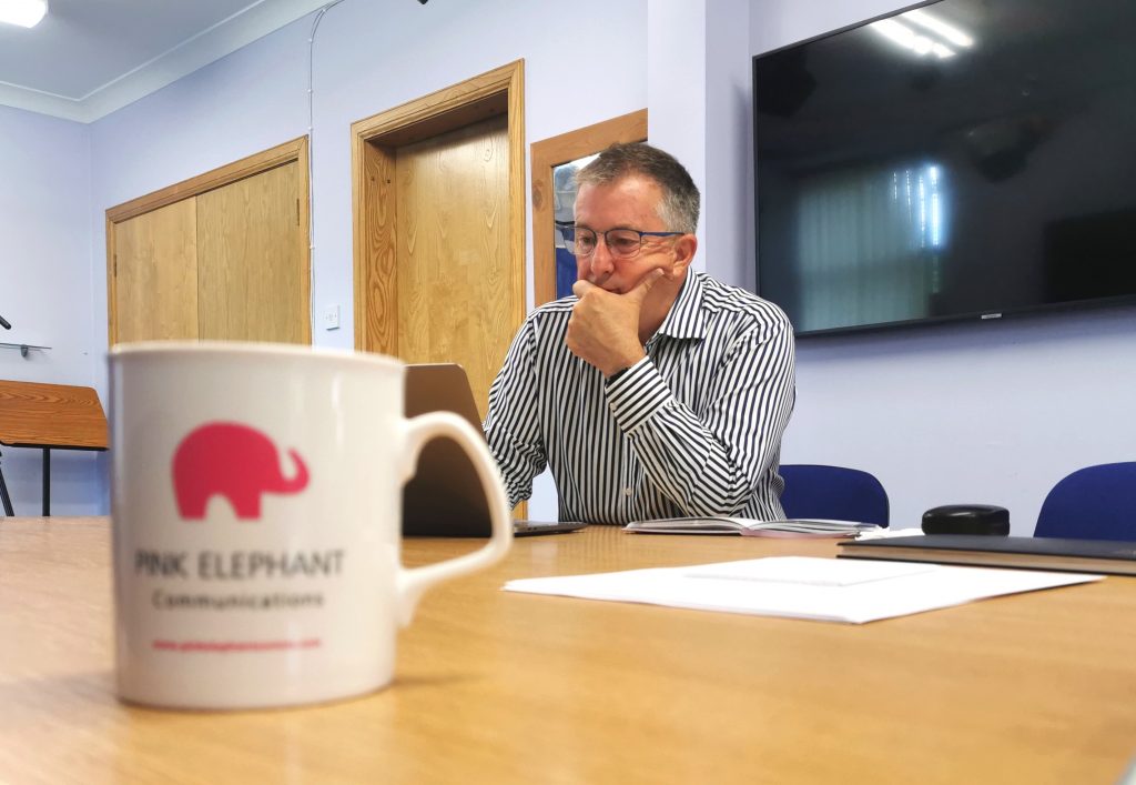 bill mcfarlan in pink elephant studio, mug on table, talk like ted training