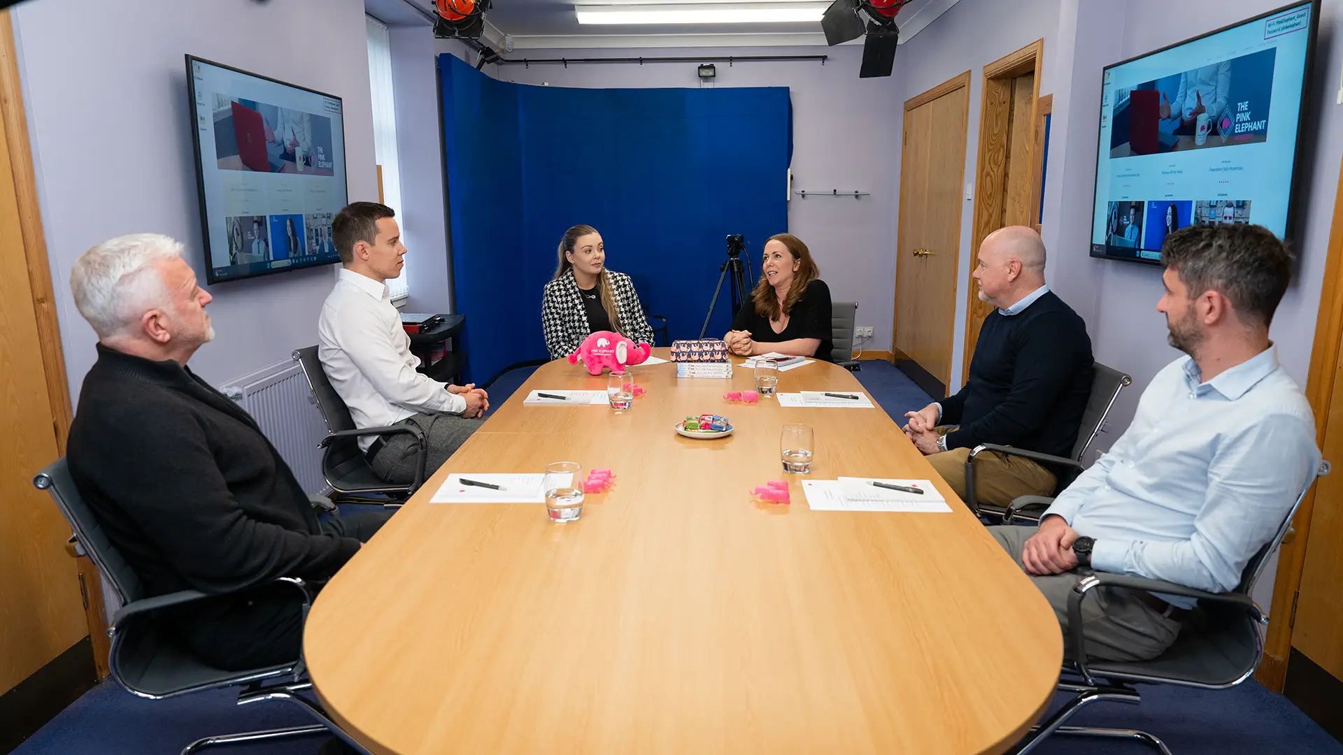 How to talk your way out of jargon; A group of professionals seated around a conference table during a group social media course, with screens and materials in the background.
